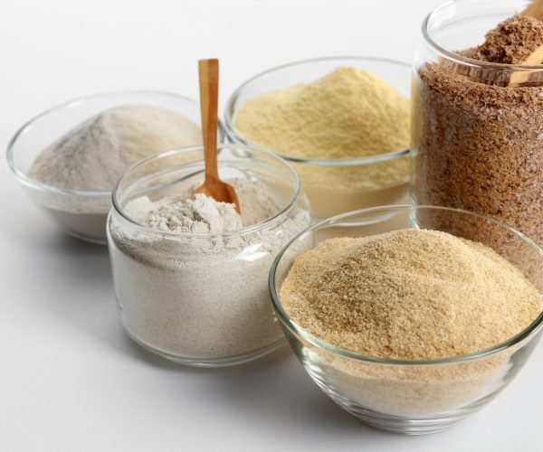 Different types of flour in bowls isolated on white