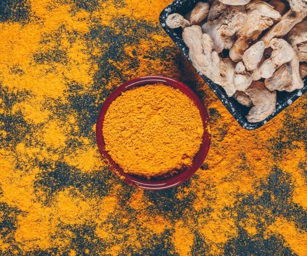 Set of ginger and ginger powder in bowls and spread around on a dark textured background. flat lay.